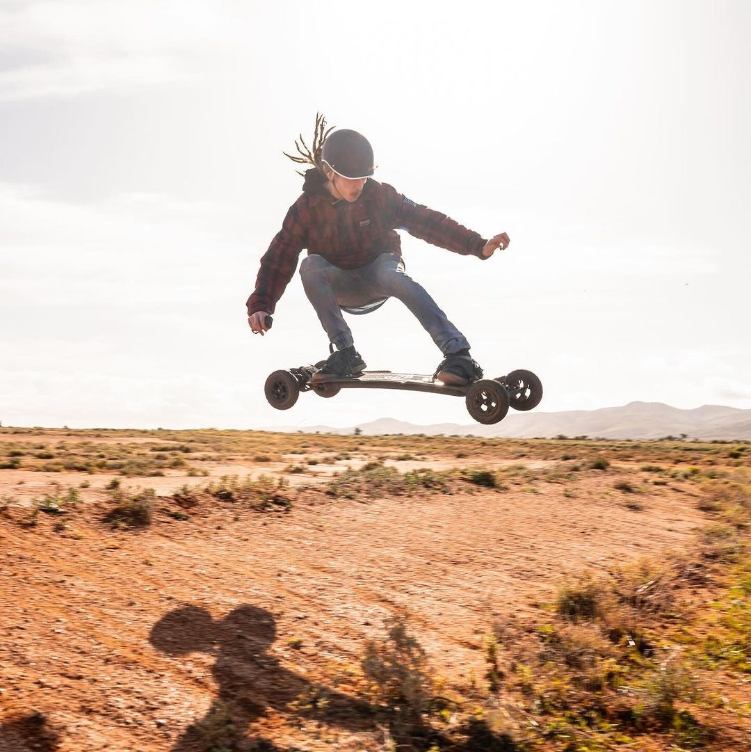 Skateboarder getting air on a black renegade off road electric skateboard with bindings from evolve.