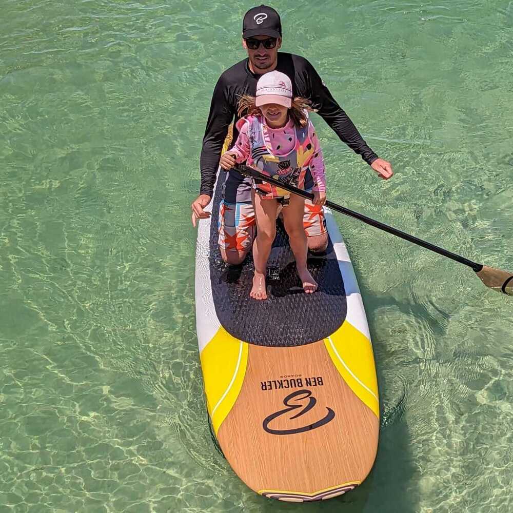 Man and child paddle boarding together on clear water