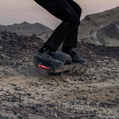 Onewheel GT carving through a dirt trail with a slick tyre