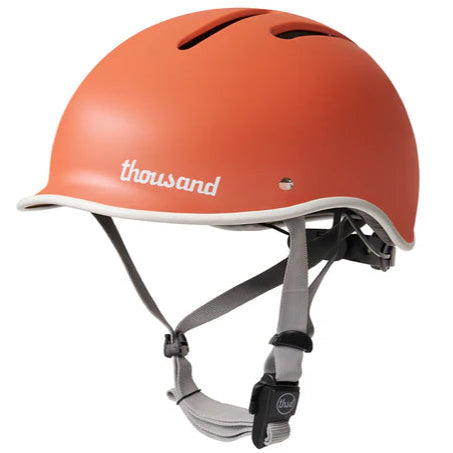 Thousand heritage 2 helmet with aprocot crush colour with white trim and logo and grey nylon straps with magnetic buckle.