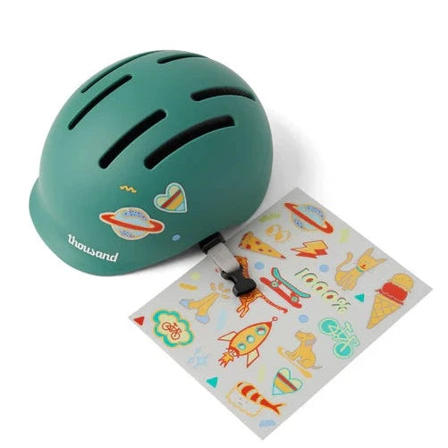 green toddler bike helmet by Thousand with a sheet of stickers.